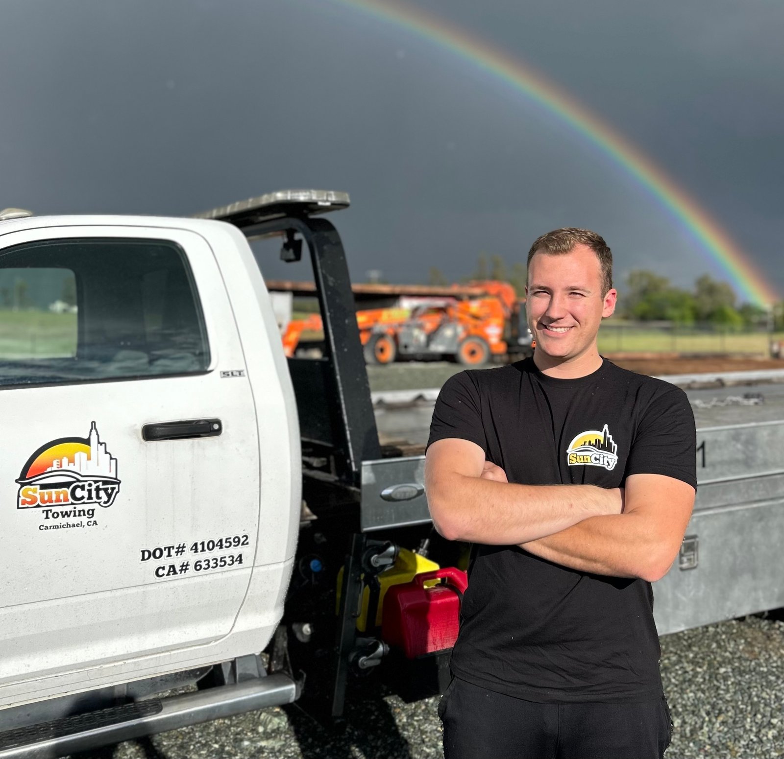 Owner of Sun City Towing standing in front of a flatbed tow truck