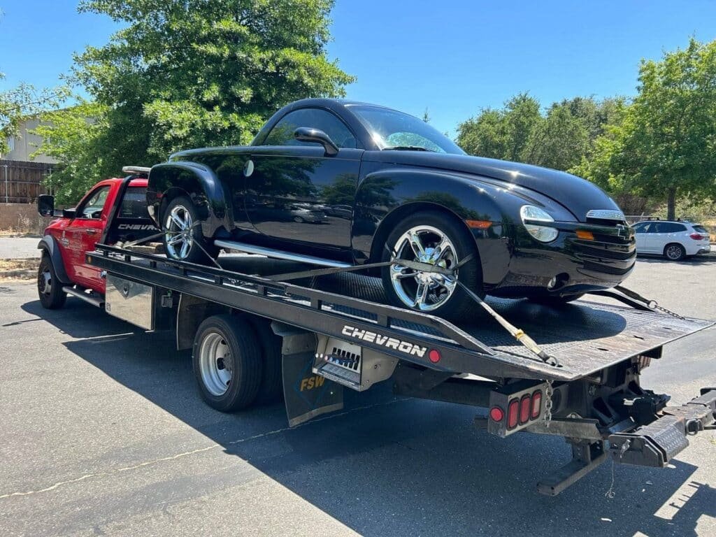Sun City Towing flatbed carrying a black convertible