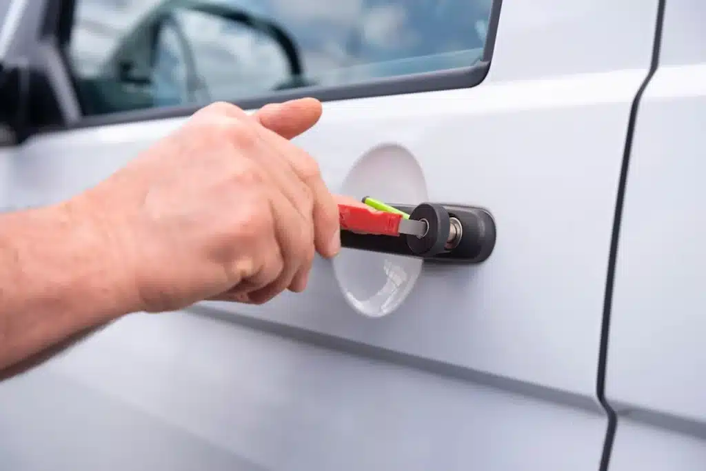 Locksmith unlocking a car door with a tool during a vehicle lockout situation.