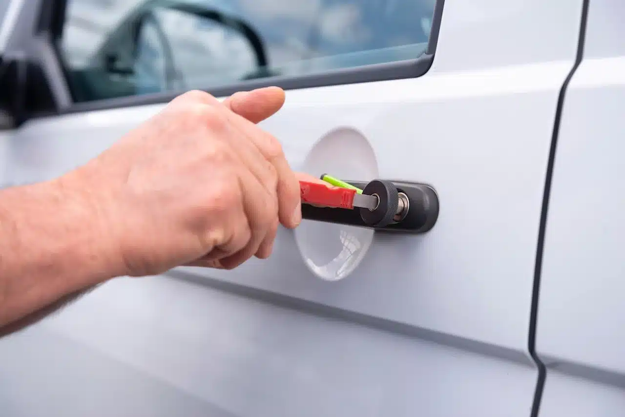 Locksmith unlocking a car door with a tool during a vehicle lockout situation.