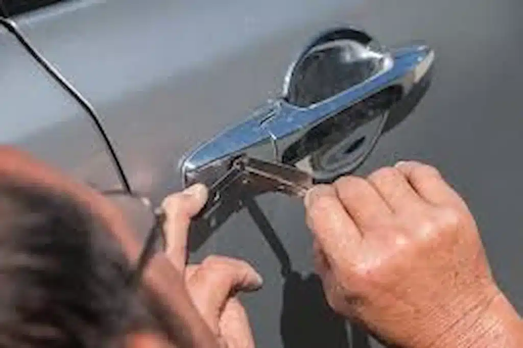 Person using a tool to unlock a car door from the outside.