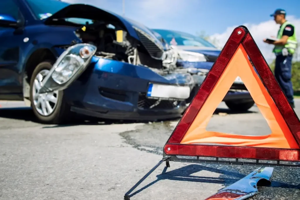 Damaged car after an accident with a warning triangle placed on the road.