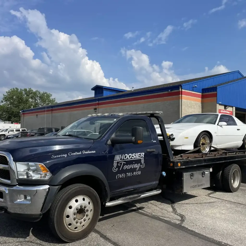 Local towing company truck transporting a car on a flatbed.