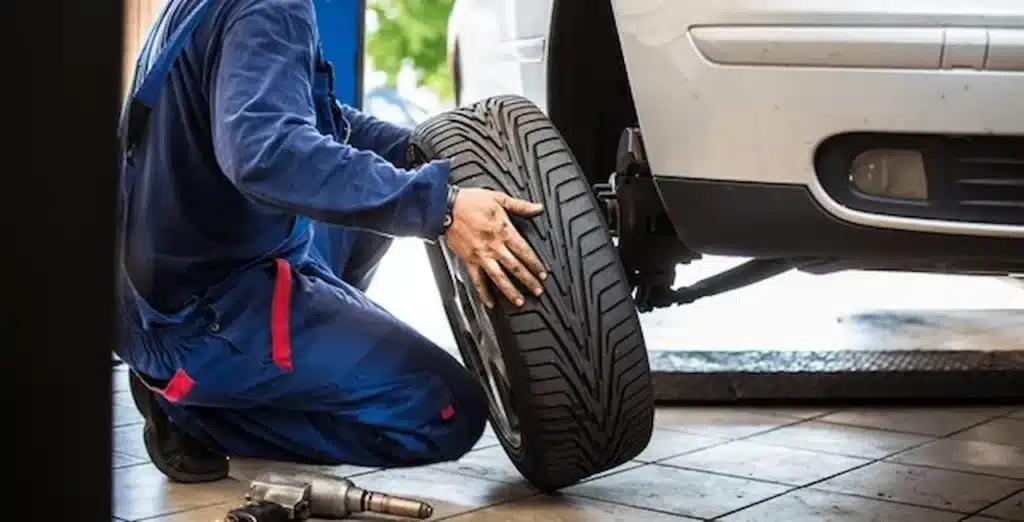 Person replacing a flat tire on a car during roadside emergency.