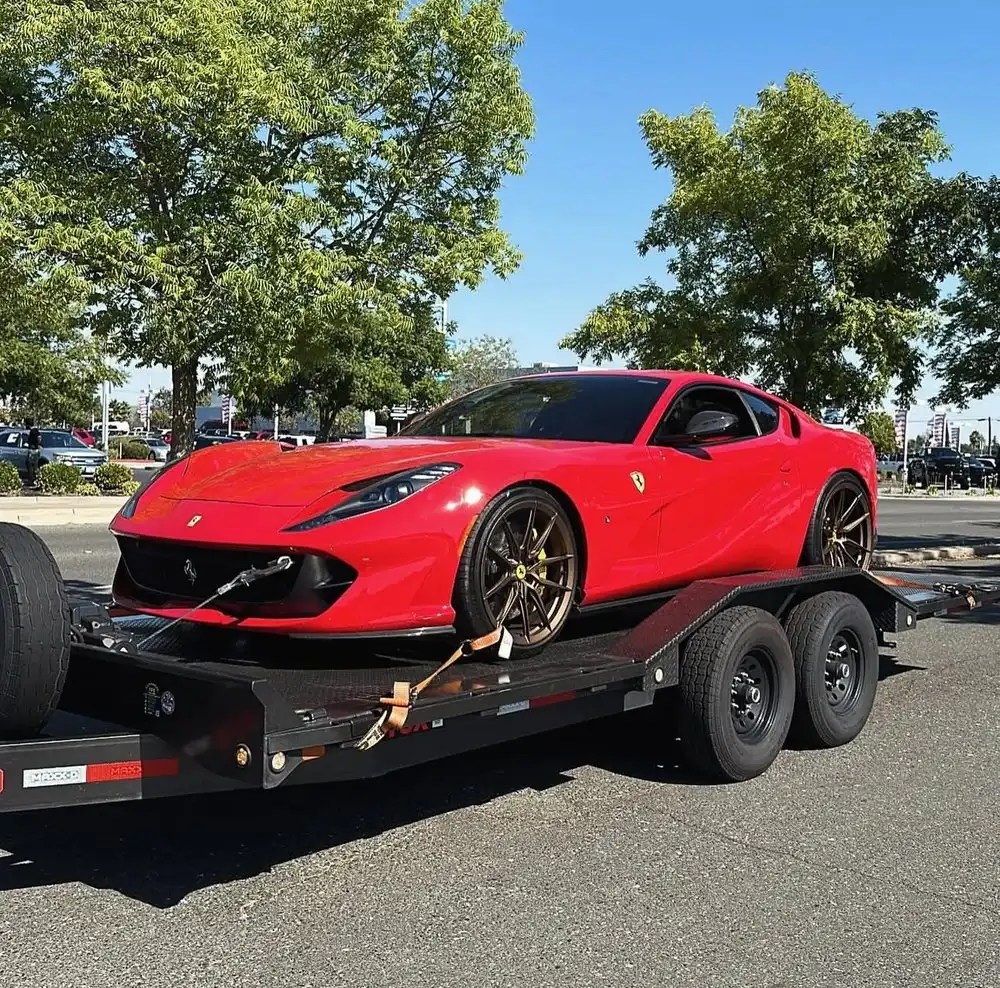 Driver calling a towing company as a flatbed tow truck transports a car in Sacramento.