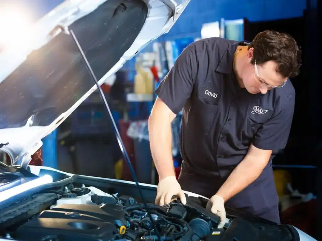 A professional roadside technician inspecting a car engine under an open hood to diagnose why it won't start.