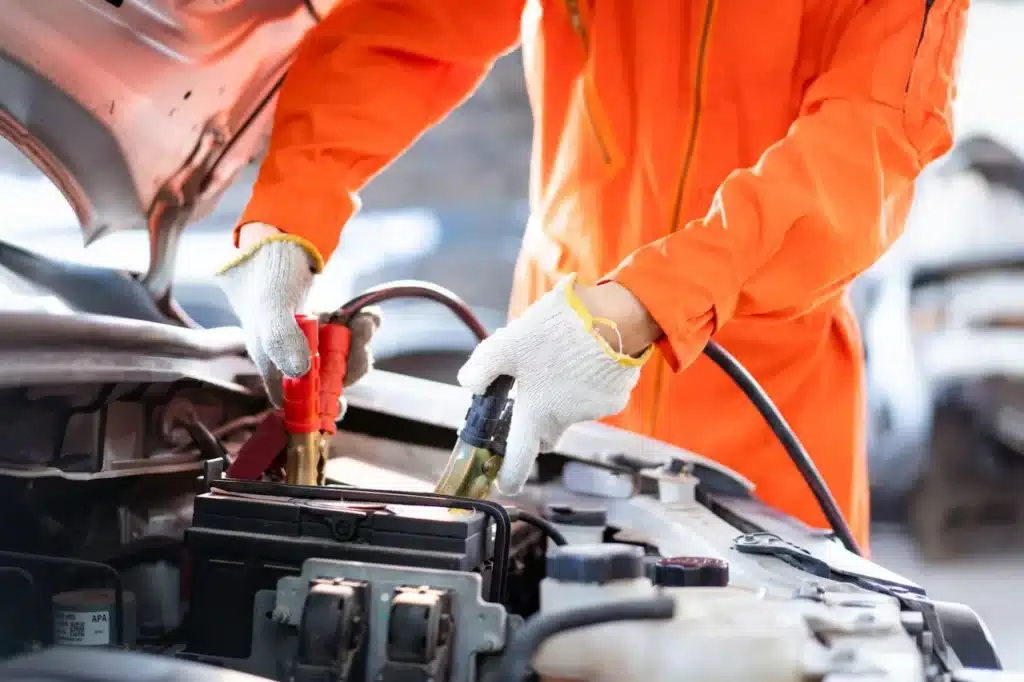 Roadside assistance technician using jumper cables to jump-start a car battery during a vehicle breakdown in Carmichael, California