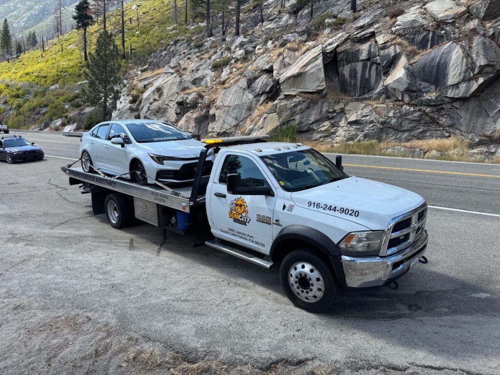 Sun City Towing flatbed hauling a white car past granite boulders in South Lake Tahoe