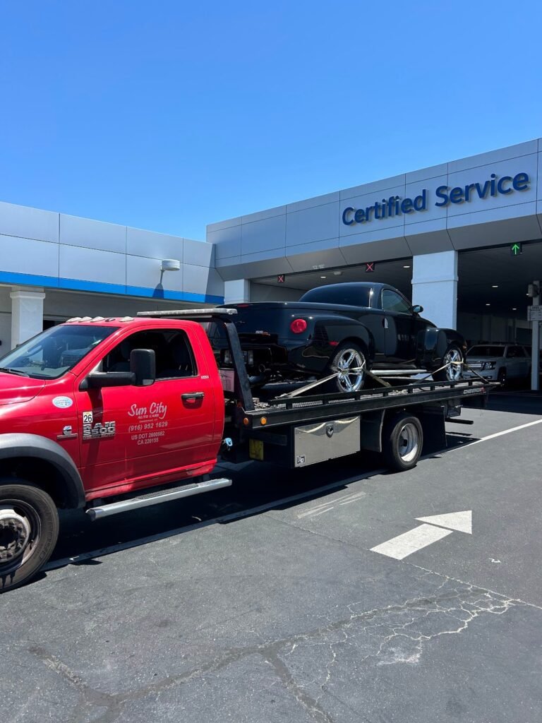 Sun City Towing flatbed delivering a car to a dealership service center