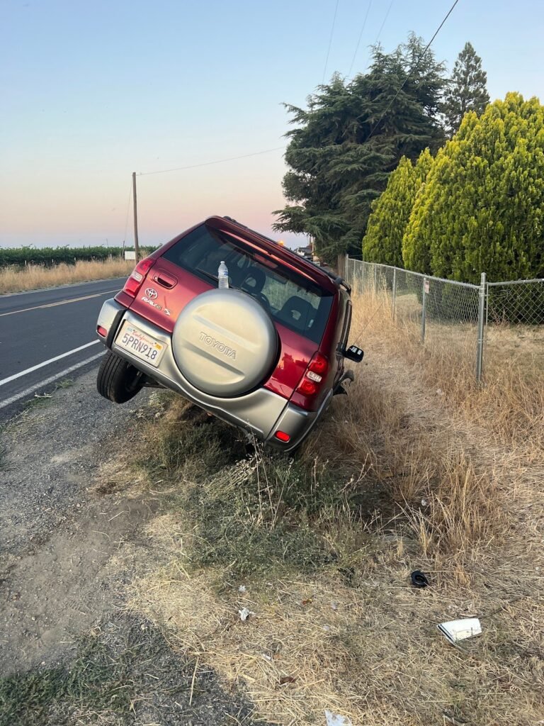 SUV stuck nose-down in a roadside ditch waiting for a winch-out