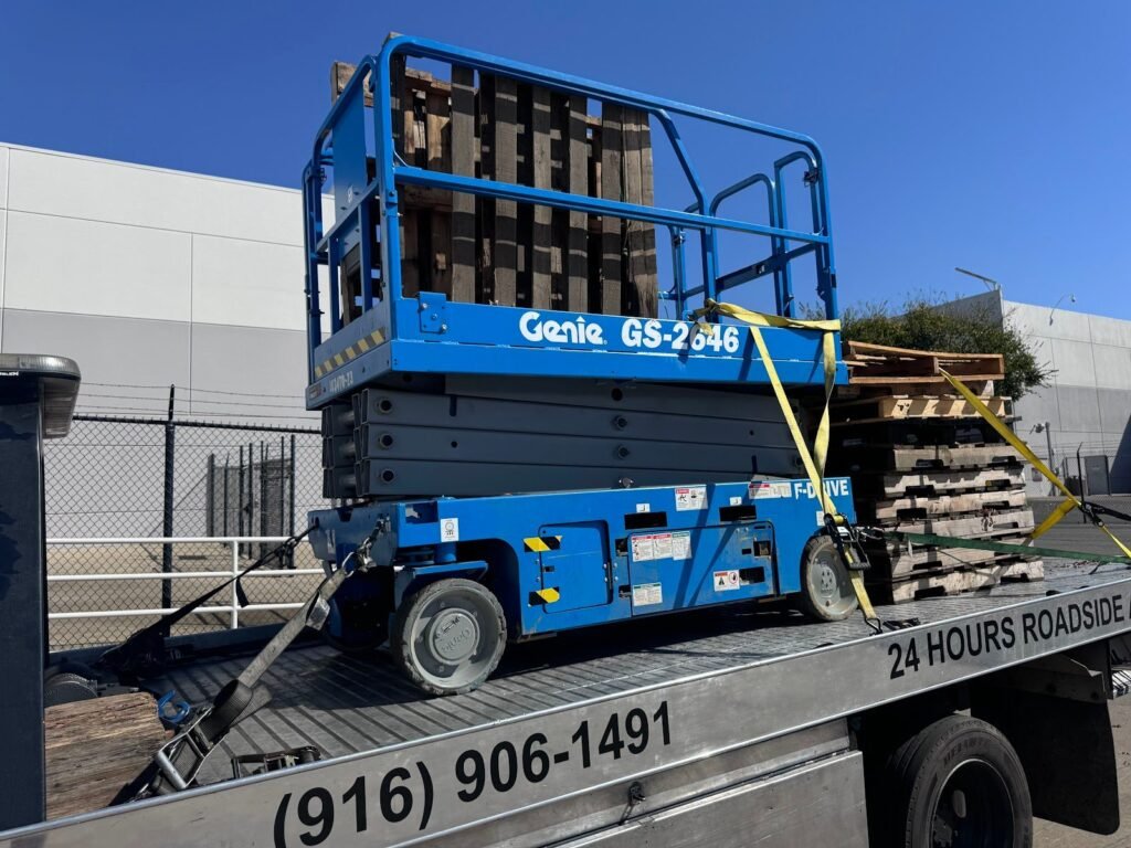 Scissor lift strapped down on a flatbed for equipment hauling